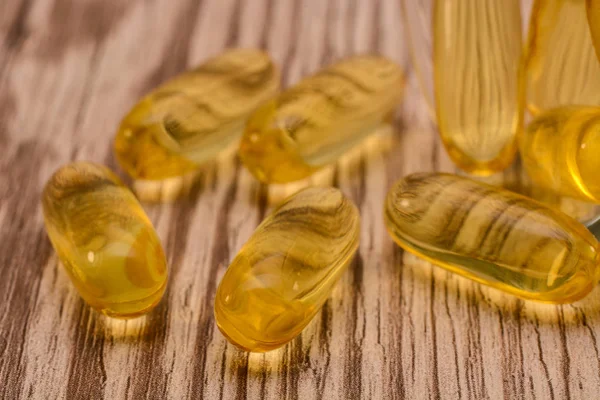 Рыбное масло желатин софтгели с омега 3 и витамин D на деревянной текстуре с солнечными лучами, концепция здорового питания — стоковое фото