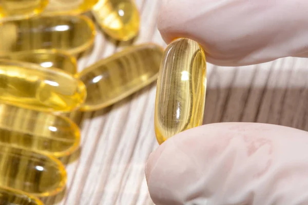 Balık yağı jelatin softgel omega 3 ve D vitamini, sağlıklı beslenme kavramı ile tutarak lastik eldiven giyiyor el