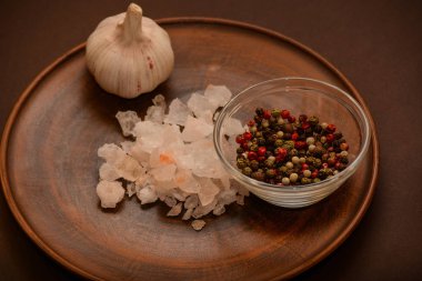 Bütün karabiber, sarımsak ve gül tuz kümesi. Kırmızı, siyah, beyaz karabiber, tuz ve sarımsak argil tabakta avuç