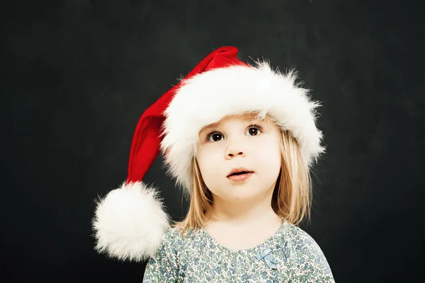 Natale bambino ragazza in Santa Hat sognare su lavagna Backgro — Foto Stock