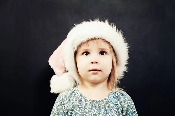 Liten flicka Santa hatt tittar upp. Gullig barn Gi — Stockfoto