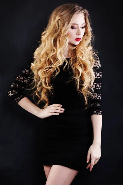 Όμορφη γυναίκα με ξανθά σγουρά μαλλιά σε μαύρο φόρεμα — Φωτογραφία Αρχείου
