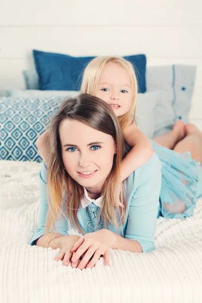 Lächelnde Mutter mit Tochter, die zu Hause auf dem Bett liegt. glücklich fam — Stockfoto