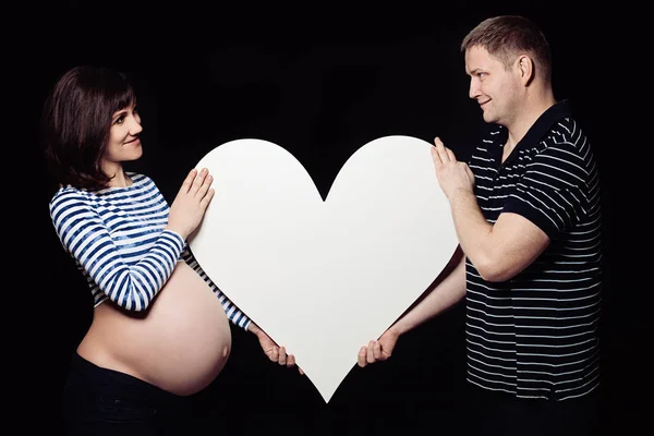 Zwangere vrouw met haar handen in de vorm van een hart op haar baby bu — Stockfoto