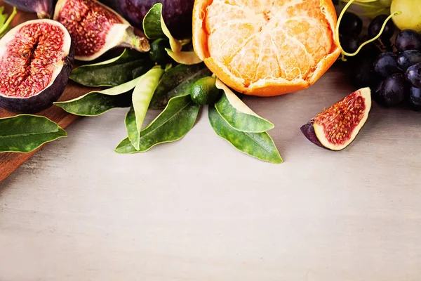 Fronteira de frutas de uva, tangerinas, figos em fundo de madeira — Fotografia de Stock
