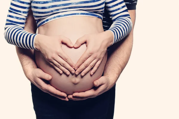 Embarazada vientre con símbolo del corazón. Hombre abrazando a la mujer embarazada y —  Fotos de Stock