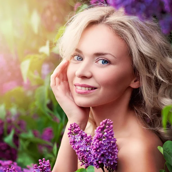 Mulher sorridente bonito com luz de verão e flores de lilás ao ar livre . — Fotografia de Stock