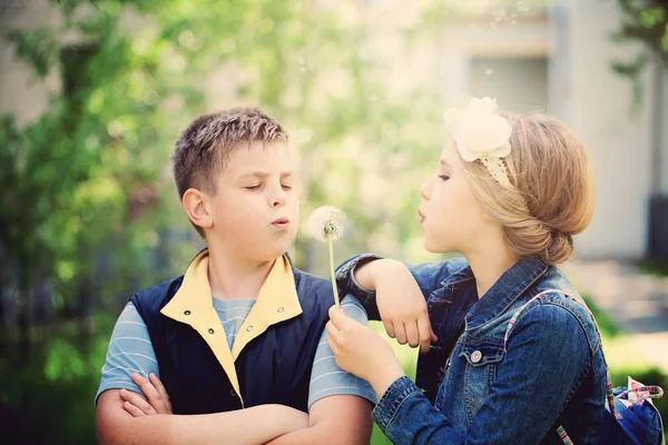 Jongen en meisje waait een paardebloem bloemen. Gelukkige jonge geitjes overtreffen — Stockfoto