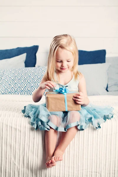 Niedliches Kind Mädchen Eröffnungsgeschenk mit blauer Schleife — Stockfoto