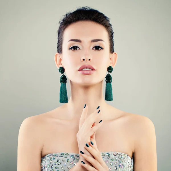 Mulher modelo bonita com maquiagem, manicure e brincos verdes . — Fotografia de Stock