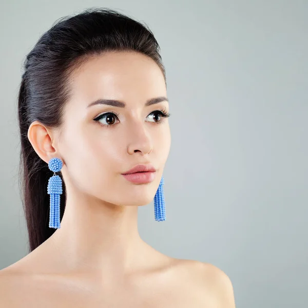 Bella giovane donna con trucco e orecchini blu — Foto Stock