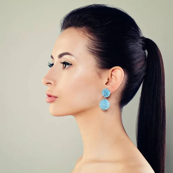Mooie jonge vrouw met blauwe oorbellen. Profiel — Stockfoto