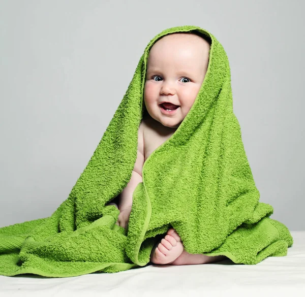 Fröhliches Baby in grünem Handtuch auf Hintergrund. Kleines Kind, 6 Monate — Stockfoto