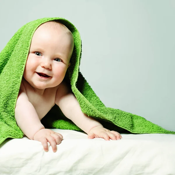 Χαρούμενος λίγο μωρό με πράσινη πετσέτα. Γέλιο μικρού παιδιού — Φωτογραφία Αρχείου