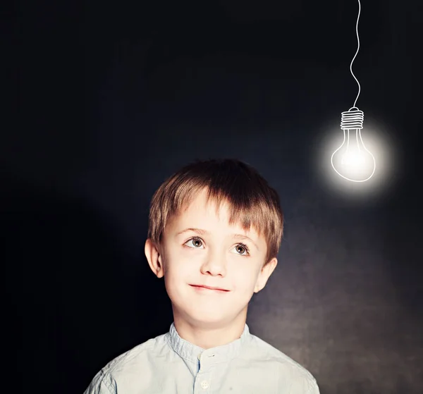 Allegro bambino sorridente con lampadina alla lavagna — Foto Stock