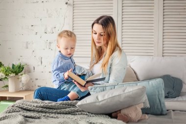 Anne ve oğlu evde kitap okurken. Mutlu bir aile 