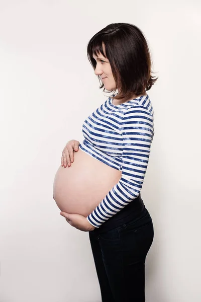 Schwangere in blauem Tuch auf grauem Hintergrund, Profil — Stockfoto