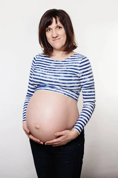 Šťastná žena těhotná na šedém pozadí — Stock fotografie