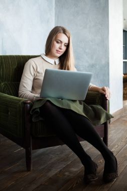 Evde dizüstü bilgisayar kullanan genç bir kadın.