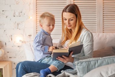 Anne ve oğlu evde kitap okurken. Mutlu sevgi dolu aile