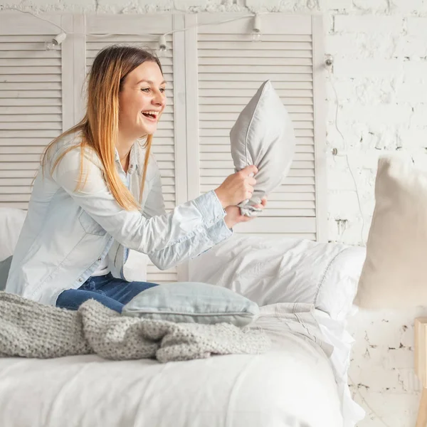 Mujer alegre divirtiéndose en casa. Movimiento, lucha de almohadas — Foto de Stock