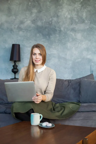 Vacker kvinna sitter på soffan och använder bärbar dator hemma — Stockfoto