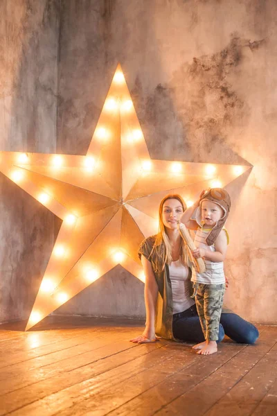 Vrolijke peuter jongen met zijn moeder op sterren studio achtergrond — Stockfoto