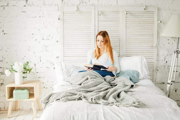 Linda pelirroja mujer leyendo libro en casa . — Foto de Stock