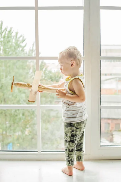 Bambino piccolo ragazzo che gioca con giocattolo aereo in legno e sognando — Foto Stock