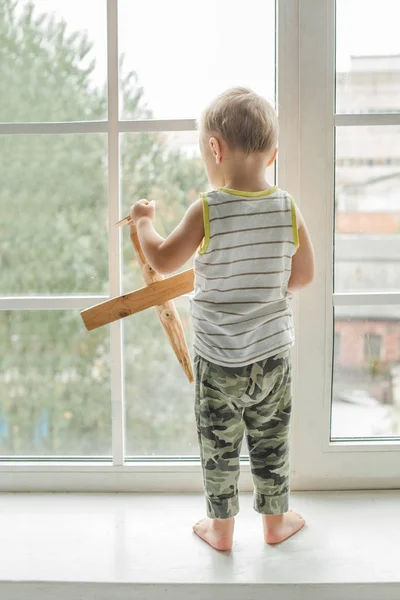 Bambino piccolo ragazzo guardando fuori dalla finestra e giocando — Foto Stock