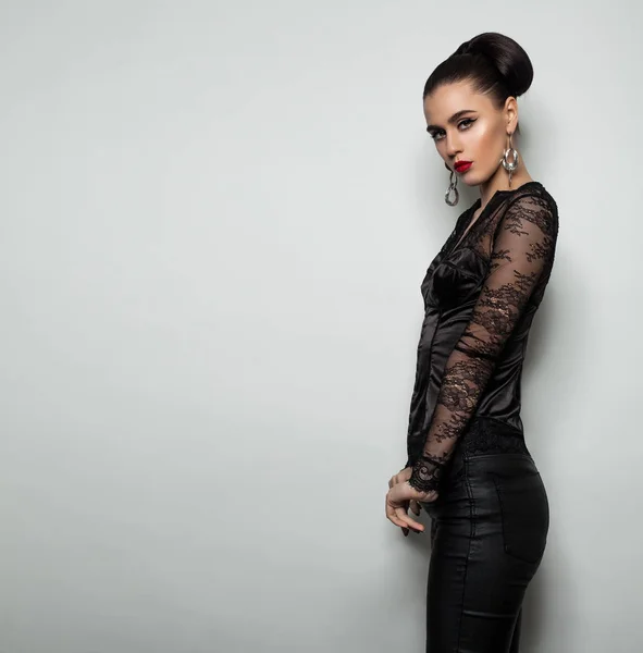 Mulher bonita em roupas pretas em pé contra a parede cinza — Fotografia de Stock