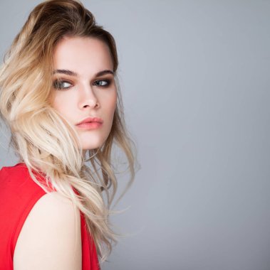 Gri arka plan üzerinde uzun sarı saçlı genç kadın