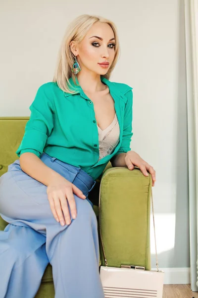 Stylish blonde woman sitting on green velvet sofa — Stock Photo, Image