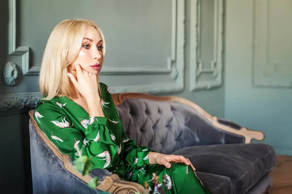 Evde koltukta oturan şık sarışın kadın.