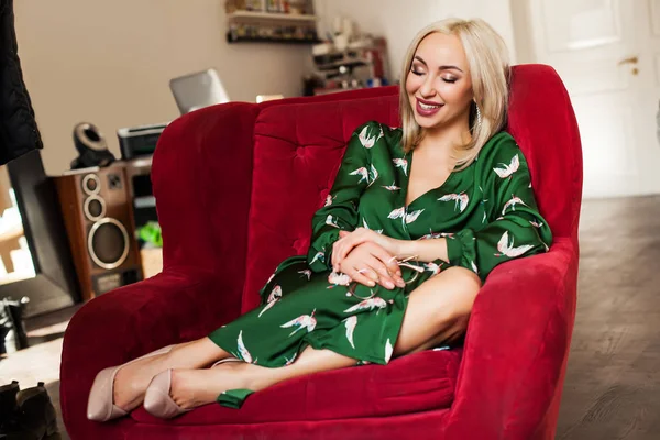 Blonde haren vrouw zittend op de rode comfortabele fauteuil — Stockfoto