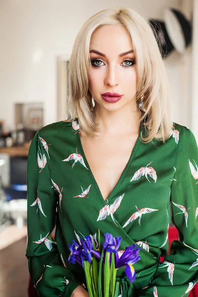 Hermosa mujer en vestido verde sosteniendo flores de iris — Foto de Stock