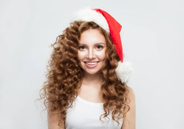 Noel Baba şapkalı güzel kadın beyaz, Noel ve yeni yılda gülümsüyor.