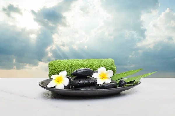 Lázeňské květiny a černé kameny se zeleným ručníkem na tmavém talíři. Lázně — Stock fotografie