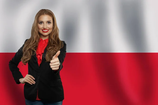 Милая молодая женщина, показывающая большой палец на фоне флага Польши . — стоковое фото