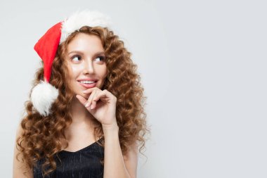 Noel Baba şapkalı kadın beyaz arka plana bakıyor.