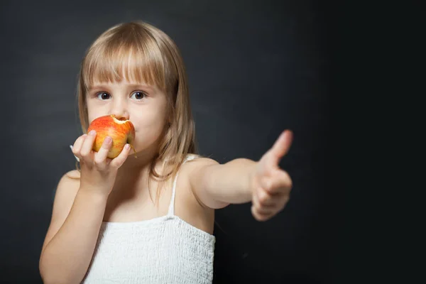 Kind eet verse rode appel gelukkig en doet ok teken — Stockfoto