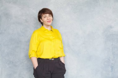 Sarı tişörtlü, gülen olgun kadın griye basıyor. 