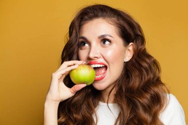 Sağlıklı, beyaz dişli, parlak sarı elma meyvesi yiyen bir kadın.