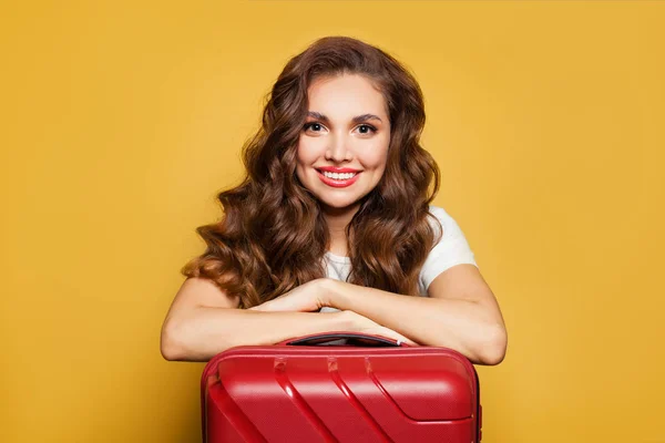 Mujer turista viajera bonita con maleta roja sobre fondo amarillo — Foto de Stock