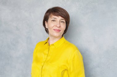 Mutlu orta yaşlı iş kadını gri arka planda, portre