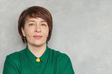 Gri arka planda kısa saç kesimi olan kendine güvenen kadın, portre