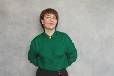 Gri arka planda gülümseyen orta yaşlı iş kadını