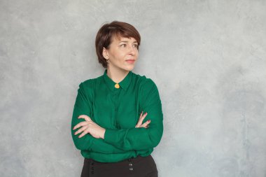 Zeki iş kadını gri arka planda, portreye bakıyor.