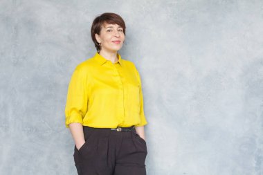 Sarı tişörtlü, gülümseyen, portresi olan olgun bir iş kadını.