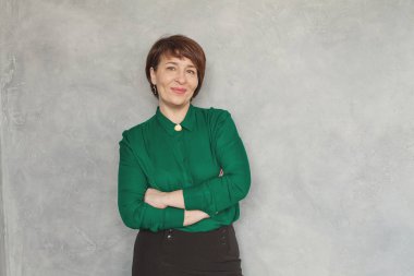 Gri kaplama arka planda yeşil tişört giyen hoş bir iş kadını.